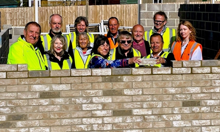 Dorset Council cabinet member for health and housing Cllr Gill Taylor laying a brick at the new CLT homes development with Kevin Hodder, director of partnership and engagement at Aster Group, watched by Portland CLT chair Andy Matthews. Left to right: Cllr Paul Kimber (Dorset Council ward member for Portland), Helen Walpole (executive assistant at Redtale), Jonathan Burt (CLT treasurer), Paul Derrien (Dorset Council housing enabling and delivery team leader), Cllr Gill Taylor (Dorset Council cabinet member for health and housing), Karon McFarlane (CLT secretary), Gary Messenger (Dorset Council interim head of housing), Andy Matthews (CLT chairman), Vic Pomeroy (CLT board member), Malcolm Curtis (chief executive, the Redtale Group), Kevin Hodder (director of partnership and engagement at Aster Group) and Lauryn Mealing (housing project and delivery assistant) - picture contributed